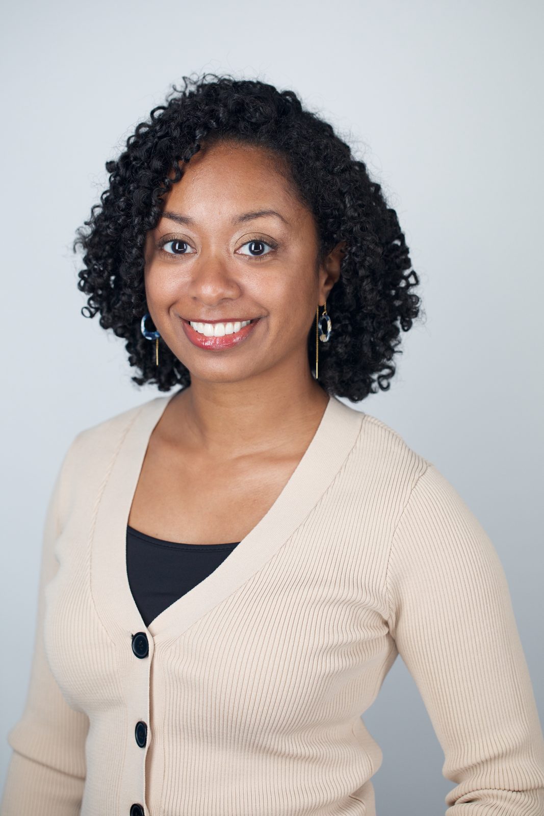 ERAS application photo example — applicant in cream cardigan over a dark top, warm smile