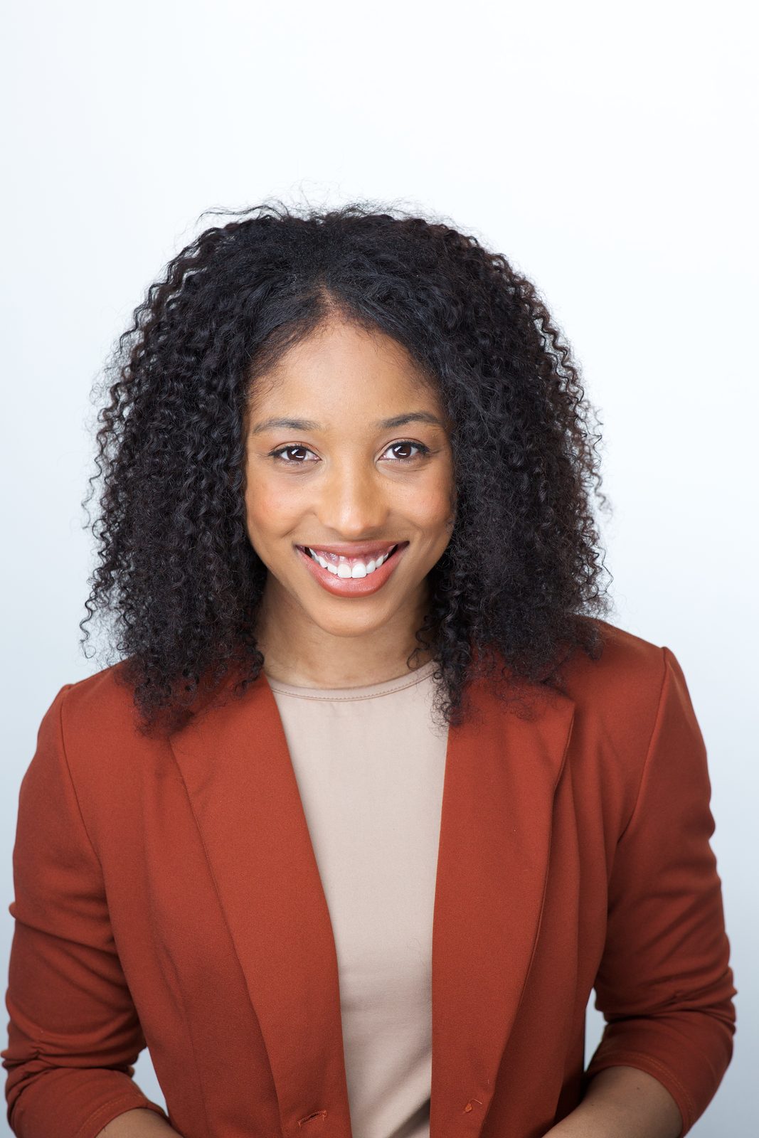 ERAS application photo example — applicant in terracotta blazer over a beige top, open warm smile