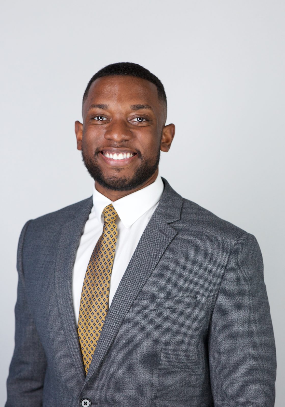ERAS application photo example — applicant in gray suit with a small-pattern gold tie, composed expression